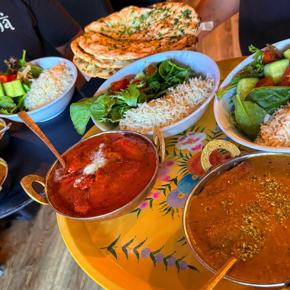 Assorted Indian dishes with rice, salads, naan, curries, and chutneys arranged on colorful serving trays.